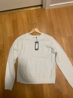 Vit stickad tröja från Vero Moda - Säljer en stilren vit stickad tröja från Vero Moda. Tröjan har rund halsringning, långa ärmar och ribbade muddar vid ärmslut och nederkant. Perfekt för lager på lager och enkel att matcha med olika outfits.