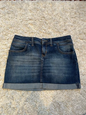 Jeanskjol  - Säljer en snygg jeanskjol från Cross Jeans med lågmidja. Perfekt till sommaren och passar till allt! Midjemått rakt över ca 38 och kjolen är 33 cm lång💗