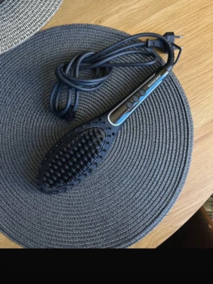 SilverCrest elektrisk värmeborste - Elektrisk värmeborste från SilverCrest i svart plast med digital display och tre knappar för enkel temperaturkontroll. Borsten har täta piggar och lång sladd, perfekt för att snabbt styla håret och få det slätt och glansigt.