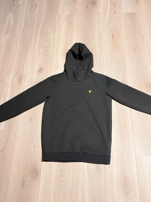 Svart hoodie från Lyle & Scott - Svart hoodie från Lyle & Scott med klassisk gul logga på bröstet. Köpt i Lyle & Scott butik. Nypris då var på 699kr