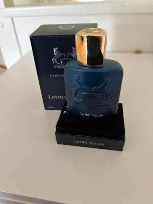 Parfyms de Marly Layton Exclusif parfym 125ml - Lyxig parfym från Parfums de Marly, Layton Exclusif Edition Royale. Flaskan är matt mörkblå med guldfärgat lock och har en elegant relief med två hästar och sköld. Volymen är 125 ml och förpackningen är stilren och exklusiv. Skriv gärna innan köp.