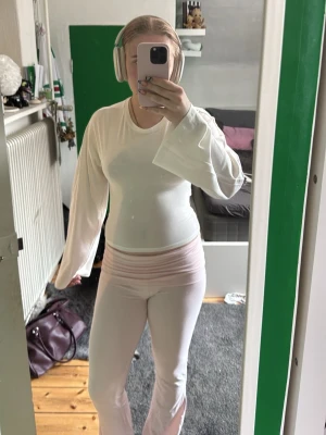 Vit topp med knyt i ryggen - Säljer en vit topp med långa, vida ärmar och snygg knytning i ryggen. Toppen har en clean look och är lätt croppad, perfekt till både jeans och kjol. Materialet känns mjukt och stretchigt, troligen bomull eller polyester. Aldrig använd