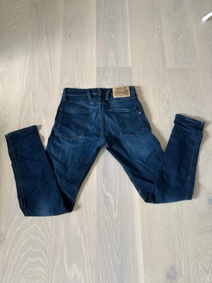 Mörkblå jeans från Replay - Snygga mörkblå jeans från Replay med klassisk femficksdesign och raka ben. Jeansen har en tydlig Replay-lapp bak i midjan och är tillverkade i slitstarkt denim. Perfekta för dig som gillar en tidlös och stilren look. Pris går att diskutera. Vid intresse är det bara att höra av sig 