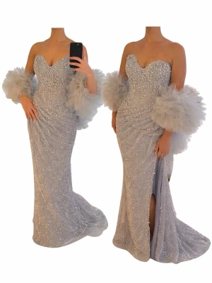 Glittrig silverlångklänning med volang - Superelegant långklänning i silver med glittrande paljetter och hjärtformad urringning. Klänningen har en figurnära passform, slits framtill och stora volangdetaljer vid armarna som är avtagbara kommer även med extra tillbehör så de går att använda klänningen på 4 olika sätt. Använd endast en gång köpt för 9000. Pris kan diskuteras 