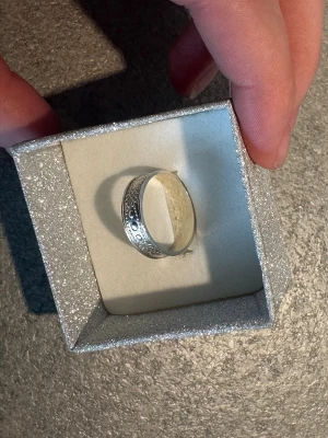 Norrbottensring - Snygg silverfärgad Norrbottensring med ingraverade blommönster och små cirkulära detaljer runt hela bandet. Ringen har en klassisk, bred form och levereras i en glittrig ask. Perfekt för dig som gillar stilrena accessoarer med unika detaljer. Jag tror det är storlek 17,5-18, minns inte men eftersom den passar mig och jag brukar ha 18. Nypris 800-900kr! I fint skick.