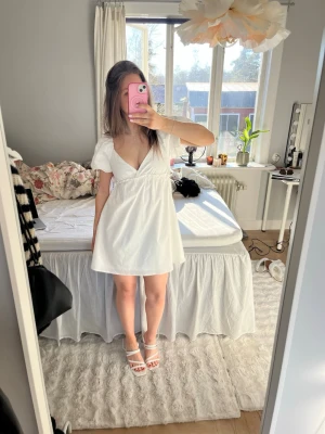 Vit kort klänning med puffärm - Söt vit klänning med korta puffärmar och djup v-ringning. Köptes till studenten men valde sedan en annan så prislapp kvar🩷studentklänning, sommarklänning, midsommarklänning