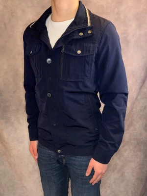 J-Lindeberg Bailey Vår/Höst Jacka - Stl S - Riktigt snygg Bailey Vår/Höst jacka från J-Lindeberg i färgen marinblå! | Mycket bra skick: 9/10, inga defekter | Stl: S, modellen är 177cm och väger 75kg, passar riktigt bra 🙌 | Hör av dig vid frågor // Galgen 🫡