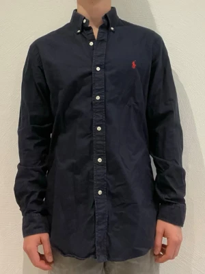 Mörkblå skjorta från Ralph Lauren - Ralph Lauren skjorta || Storlek M (Custom fit) || Skjortan är i bra skick || Modellen på bilden är 170cm och väger 62kg || Tveka inte på att höra av dig vid frågor eller funderingar 