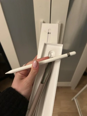 Apple Pencil första generationen - Säljer en Apple Pencil (första generationen) i vit färg. Kommer i originalförpackning. Pennan är slimmad och har en matt finish med silverfärgad detalj vid toppen. Perfekt för iPad-användare som vill rita eller anteckna digitalt.