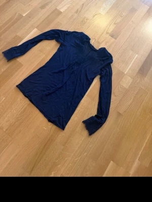 Mörkblå intimissimi tröja - Snygg mörkblå intimissimi topp med spetsdetaljer vid halsringning och ärmslut. Figurnära passform som framhäver siluetten och ger en elegant look. Perfekt att styla med jeans eller kjol för en trendig outfit.