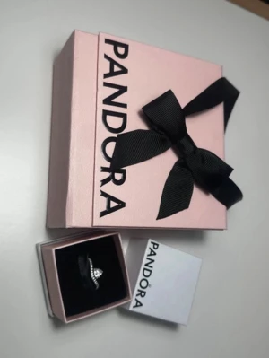 Silverring med sten från Pandora - Ny, passar en tunnare hand. Säljs med originalkartong och stor kartong tillsammans. Ringen mättes på pekfingret, jag bifogar ett måttfoto (det sista), den är 6,2 cm (62 mm) Onlinepris 799 kr.