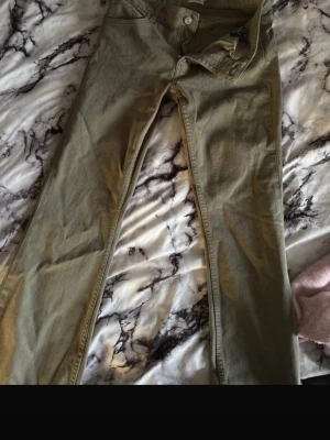 Jeans - Säljer ett par olivgröna jeans med bootcut passform. Jeansen har klassisk femficksdesign, knappgylf och raka ben som blir vidare nedtill. Perfekta för dig som vill ha en avslappnad men ändå trendig look. M men passar S
