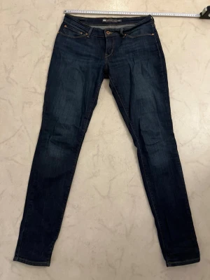 Levi's Demi Curve Skinny Jeans - Mörkblå skinny jeans från Levi's Demi Curve med mid rise passform. Klassisk femficksdesign, snygga kontrastsömmar och kopparfärgade nitar. Perfekta för dig som gillar en tight och stilren look.