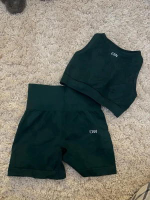 Mörkgrönt träningsset från ICANIWILL - Snyggt mörkgrönt träningsset från ICANIWILL med matchande crop top och shorts. Setet har en tight passform och är gjort i ett stretchigt funktionsmaterial som passar perfekt till gymmet eller löpning. Diskret logga på både toppen och shortsen. Aldrig använda utan enbart testade aå i nyskick💚