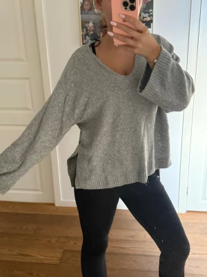 Grå oversized stickad tröja - En grå stickad tröja med v-ringning och långa ärmar. Såå fin att använda nu under de kalla dagarna men också när man bara vill vara hemma! Använd ett fåtal gånger!💞