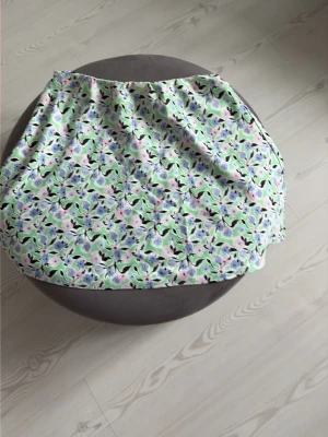 Blommig kortkjol i pastellfärger - Söt kortkjol med blommigt mönster i pastelliga toner av grönt, blått, rosa och vitt. Kjolen har en mjuk och flowy form som ger en avslappnad vibe. Perfekt för dig som gillar färg och mönster!