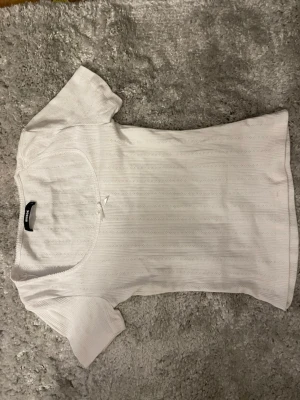 Vit topp med spetsdetaljer med en liten rosett  - Vit topp med spetsdetaljer med en liten vit rosett fram till, storlek S har nästan aldrig använt den, tunn och mjuk helt perfekt på en sommar dag, från armhålan och ner är den 32cm och från axel till axel är den 37cm skriv om du vill få reda på något mer 