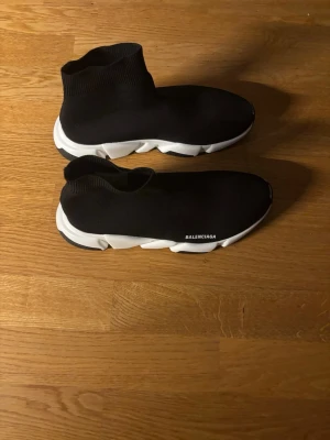 Speed Trainer sneakers svart - Säljer ett par svarta sneakers med vit chunky sula och stickad ovandel i strumpmodell. Minimalistisk design med modern logga på sidan. Perfekta för dig som gillar streetwear och vill ha något bekvämt och stilrent.