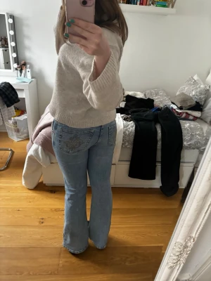 Ljusblå bootcut jeans med brodyr - Säljer ett par ljusblå bootcut jeans med snygg broderad detalj på bakfickan. Lågmidjade. Säljer då de är på gränsen till för små, och därav att de sitter som de gör på mig, annars supersnygga! 