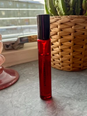 Röd parfymflaska med svart kork - En stilren parfymflaska i rött glas med svart kork. Flaskan är cylinderformad och kompakt, perfekt att ha med sig i väskan. Passar dig som gillar snygga detaljer på parfymhyllan.