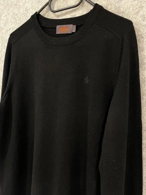 Svart merinoull tröja från Morris - Säljer denna snygga svart merinoull tröjan från Morris med rund halsringning och broderad logga på bröstet. Riktigt fin och i storlek S. perfekt året runt!