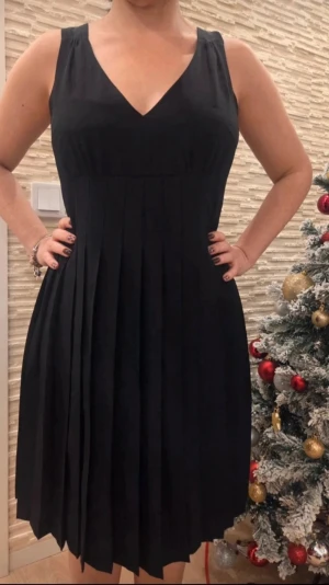 Marc by Marc Jacobs siden 100% - Snygg svart klänning med v-ringning och breda axelband. Kjolen är plisserad och klänningen har en lång dragkedja i ryggen. Perfekt för dig som gillar en klassisk men modern look. 100% siden