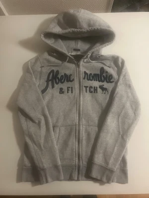 Grå hoodie från Abercrombie & Fitch - Riktigt snygg Abercrombie tröja i grå färg. Storlek S och fint skick inga fel. Pris 550 kr 😃