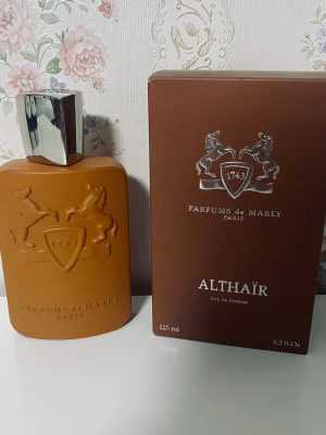 Parfums de Marly Althaïr EdP 125ml - Exklusiv parfym från Parfums de Marly, Althaïr Eau de Parfum. Flaskan är matt brun med silverfärgat lock och har ett elegant reliefmönster med två hästar och sköld. Kommer i matchande brun kartong med silverdetaljer. Volym: 125 ml.
