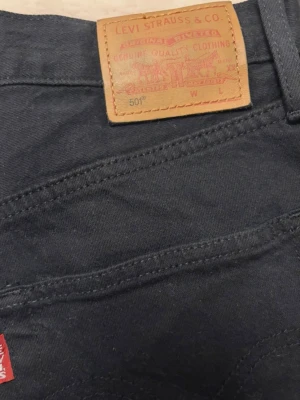 Levis jeans W27 L30 - Svarta jeans från Levi's 501-modell. Jeansen har knappgylf och klassisk femficksdesign. Passar för en tidlös stil. Rökfritt hem. Använda en gång, nypris 1199kr