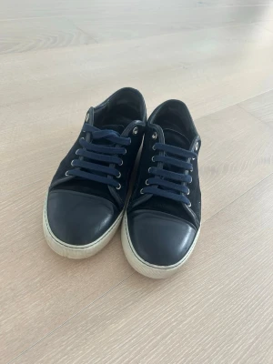 Lanvin sneakers strl 42  - Säljer ett par stilrena sneakers från Lanvin i storlek 42. Klassisk modell i mörkblå mocka med lädertå och vit sula.  Skorna är använda men i bra skick. Normalt slitage på sulan Inga större skador.    Ingen kartong eller dustbag  Storlek 42   Nypris ca 5 000–7 000 kr. Säljes för 1 850 kr   Hör av dig om du vill ha fler bilder eller undrar något!
