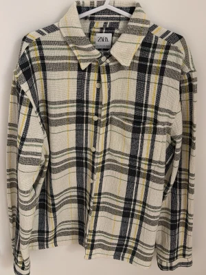 Rutig skjorta från Zara i relaxed fit - Säljer en rutig skjorta från Zara i relaxed fit. Skjortan har en bas i vitt med svarta, gula och gröna rutor, klassisk krage och knappar framtill. Materialet är grovt vävt och ger en cool, avslappnad vibe. Perfekt för dig som gillar oversized känsla.