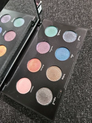 Urban Decay Moondust ögonskuggspalett - Urban Decay Moondust ögonskuggspalett med åtta skimrande nyanser i färger som grön, blå, lila, rosa, silver, guld och koppar. Paletten har en spegel och ett glittrigt svart fodral med logga. Perfekt för dig som älskar färgstarka och glittriga looks.