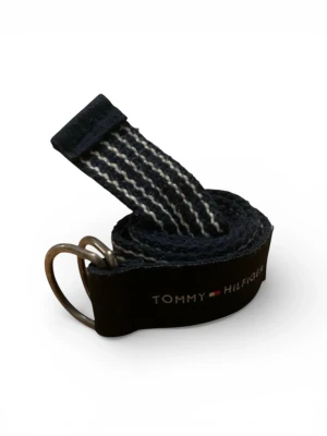 Randigt bälte från Tommy Hilfiger - Snyggt randigt bälte från Tommy Hilfiger i marinblått och vitt med dubbla metallringar som spänne. Bältet har en klassisk logga på ena änden och är gjort i ett slitstarkt tygmaterial. Perfekt för att lyfta vilken outfit som helst.