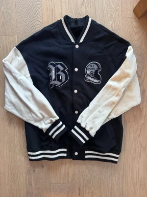 Varsity college jacket - Mycket fin och oanvänd Varsity college jacket från H&M. Retro, sport grafik med fina sydda emblem. Oversize unisex (passar alla storlekar mellan S-M), boyfriend jacket. Jackan har ribbade muddar med vita ränder och tryckknappar. På ryggen finns broderad text: 'U.S. Football '76-'79 League Champs '79'. Perfekt för en sportig streetstil.