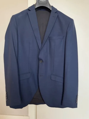 Mörkblå kostym från Selected Homme - 3 - delad kostym från Selected Home i mycket bra skick. Endast använd vid ett tillfälle. Perfekt till student eller liknande. Storlek 46 (S)