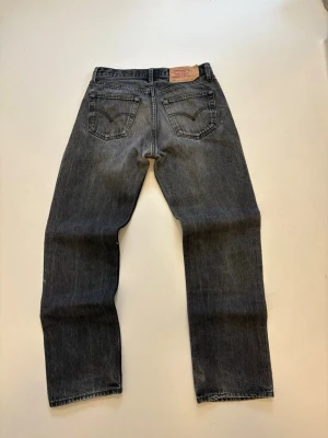 Vintage Levis jeans - Svart/gråa vintage Levis jeans 100% bomull //  Modell: 501 straight fit //  Mycket bra skick //  Storlek W33 L32 //  Mått  Midja bredd 40cm  Längd 105cm  Innerben längd 78cm  Lårvidd 30cm  Benöppning 20cm  Skriv vid minsta fråga eller fundering🤝