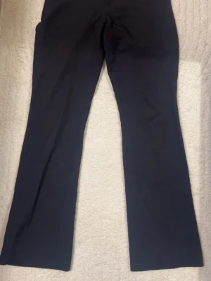 Svarta kostymbyxor med utsvängda ben - Säljer ett par svarta högmidjade kostymbyxor med raka ben. Inga synliga detaljer eller fickor på framsidan.