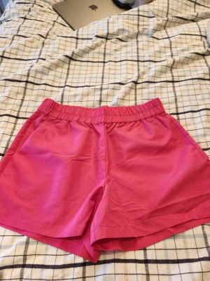 Rosa shorts från Noisy May - Snygga rosa shorts från Noisy May med elastisk midja och avslappnad passform. Ett par tränings/badshorts som aldrig använts då dem är för stora.