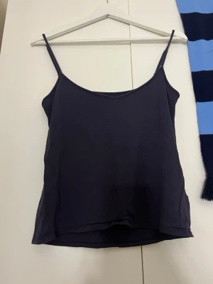 Blått linnetopp med smala axelband - En enkel och stilren blått linnetopp med smala axelband och rak passform. Perfekt att matcha med jeans eller kjol för en clean look. Tillverkad i mjukt material som känns skönt mot huden.