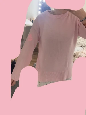 Ljusrosa stickad tröja - Söt ljusrosa stickad tröja med rund halsringning och långa ärmar. Tröjan har ribbade muddar vid ärmslut och nederkant samt en rak, avslappnad passform. Perfekt för lager på lager och enkel att matcha med jeans eller kjol.