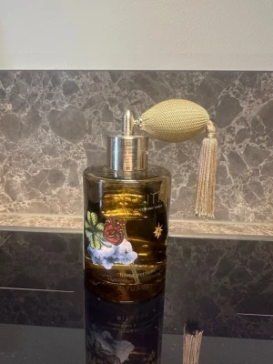 rituals intuitia rumsdoft  - Elegant parfymflaska från Rituals i glas med guldfärgad pump och dekorativ tofs. Flaskan har ett vackert fjärilsmotiv och stjärndetaljer på framsidan. Perfekt som snygg inredningsdetalj i badrummet eller på sminkbordet.