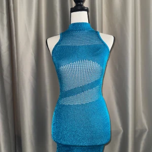 Blå skimrande stickad klänning - Säljer en turquoise blå mini klänning med   meshdetaljer. Klänningen är ärmlös och har en kroppsnära passform med transparenta partier både fram och bak. Perfekt för dig som vill sticka ut med en unik och trendig look.