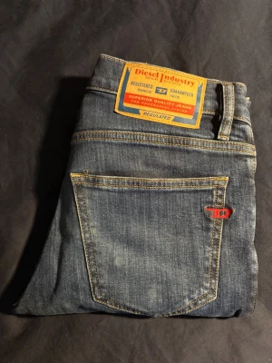 Blå slim fit jeans från Diesel - Snygga blå slim fit jeans från Diesel med klassisk femficksdesign. Jeansen har en liten röd Diesel-logga på bakfickan och patch i läderlook bak i midjan. Perfekta för en trendig och avslappnad stil. Waist 27 & Längd 30