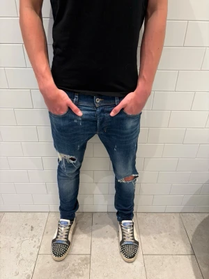Diesel jeans med slitningar - Ett par feta mörkblå diesel jeans med slitningar både bak och fram. Tveka inte att höra av er med frågor! Priset är inte hugget i sten
