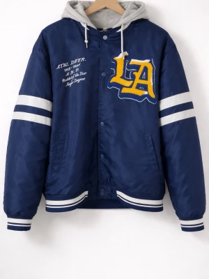 Blå bomberjacka med LA-tryck - Snygg blå bomberjacka med stora LA-bokstäver i gult och vitt på bröstet samt broderad text. Jackan har vita ränder på ärmarna och muddar i blått och vitt. Grå huva i sweatshirtmaterial ger en cool lager-på-lager-look. Perfekt för dig som gillar streetwear.