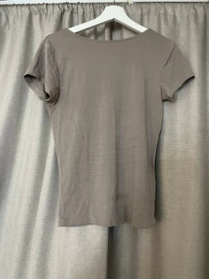 Beige t shirt med öppen rygg - Snygg beige topp med korta ärmar. Öppen rygg. Sitter mer som en s
