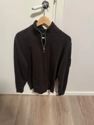 Sv fresh svart halfzip hoodie - Snygg svart halfzip hoodie från Moose Knuckles med hög krage och dragkedja framtill. Tillverkad i mjukt bomullsmaterial och har ribbade muddar. På ärmen sitter ett metallmärke med logga som ger extra edge till looken.