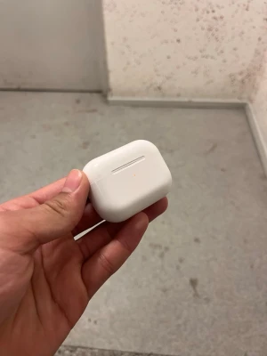 Vita trådlösa hörlurar i laddetui - Säljer ett par vita trådlösa hörlurar lastade i ett kompakt laddetui. Etuiet är gjort i blank plast och har en smidig, rundad form som är lätt att ta med sig. Perfekt för dig som vill ha musik eller poddar på språng utan sladdar.