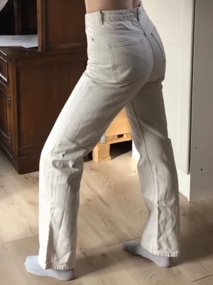 Vita raka jeans med hög midja - Supersnygga vita jeans med rak passform och hög midja. Jag gillar verkligen hur dessa jeans sitter. De är både avslappnande men stiliga. Jag bara använder inte jeans så mycket längre. Jeansen har klassiska framfickor som faktiskt är stora nog att ha något i, och bakfickor. De stängs med dragkedja och knapp. Materialet är kraftigt denim i bomull och färgen är gräddvit. Från Weekday i modellen Rowe, W28 L32. Midja: 36,5cm Innerbenslängd: 79cm Byxans längd: 109cm
