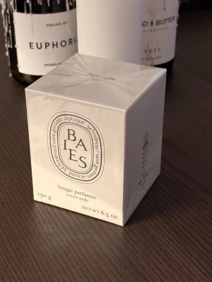 Diptyque Baies doftljus 190g - Säljer ett exklusivt Diptyque Baies doftljus i originalförpackning. Ljusets förpackning är vit med klassisk oval logga och text i svart. Innehåller 190g och har en fräsch doft av bär och rosor. Perfekt för att skapa en lyxig känsla hemma.